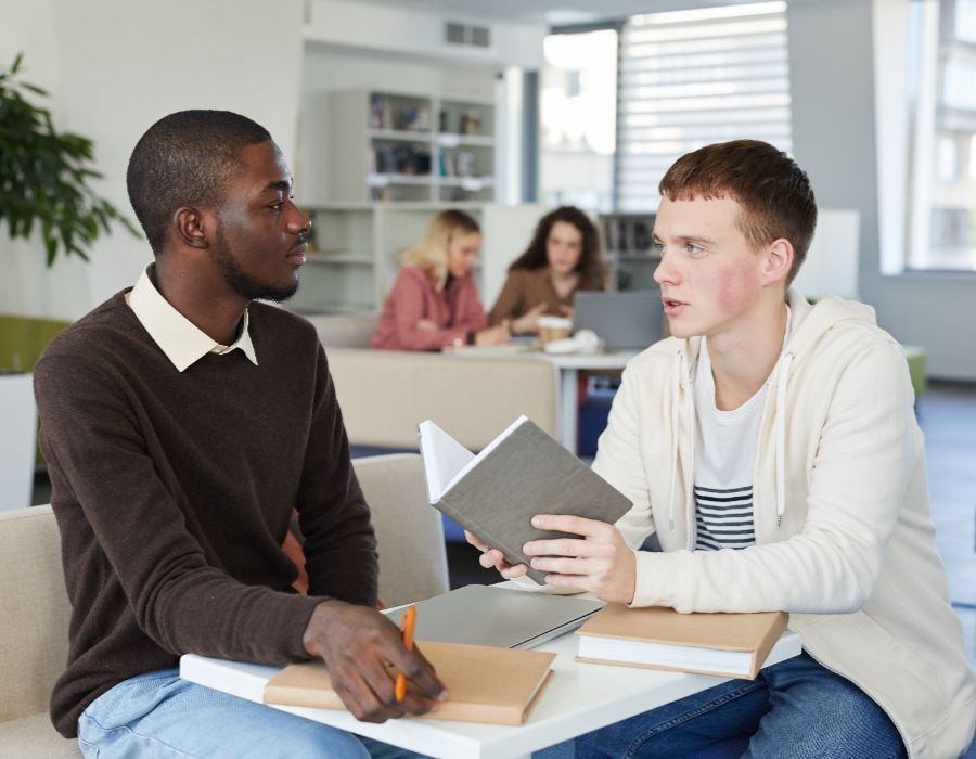 Two students discussing over books.