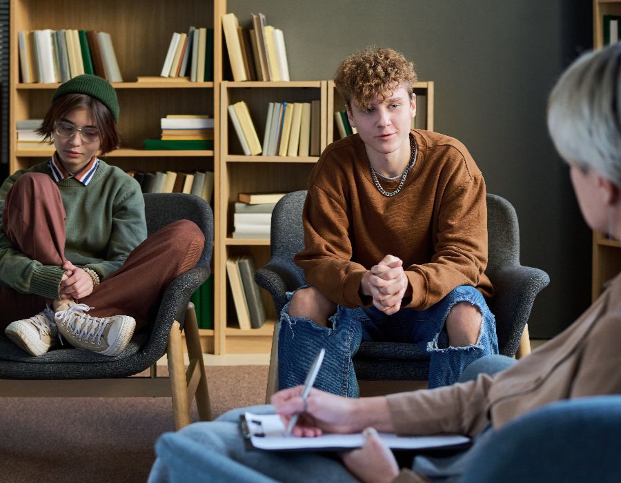 Two teens engaged in discussion with adult